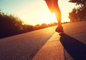 Closeup of runner's legs as they sprint down a road at sunrise